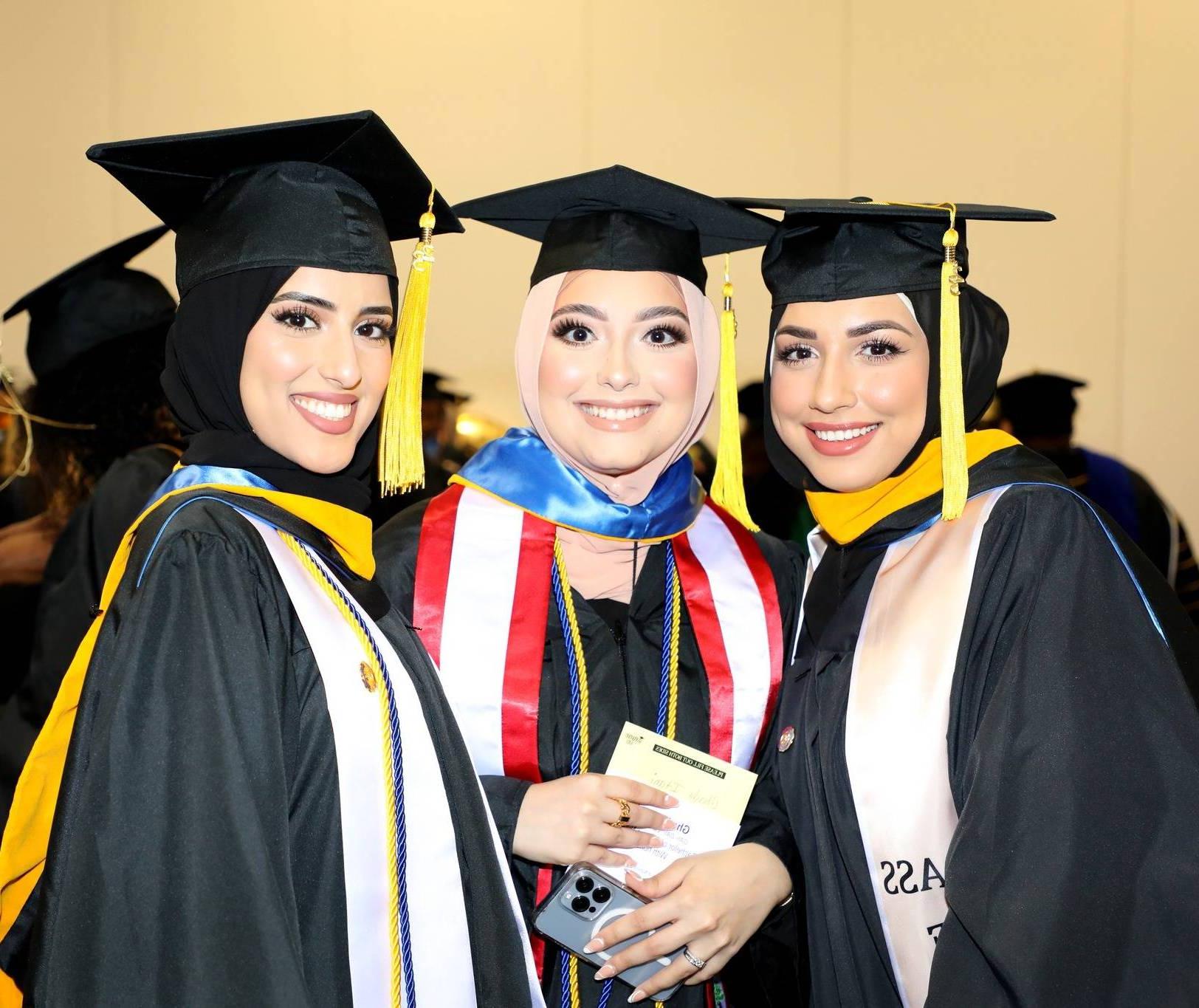 三位毕业生在2023年毕业典礼上微笑着